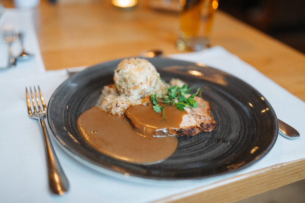 Aufgeschnittenes Fleisch mit brauner Bratensoße, Knödel und Beilage in einem Restaurant in St. Anton.
