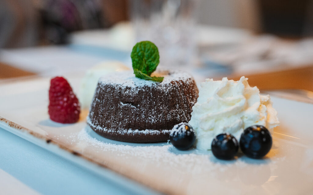 Schokoladen-Lavakuchen mit Schlagsahne, Beeren und Minze im Restaurant St. Anton.