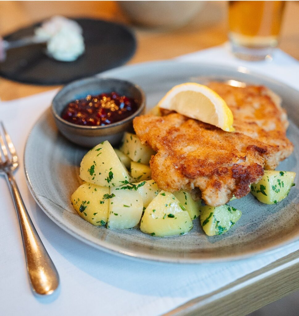 Paniertes Schnitzel mit Kartoffeln und Soße, auf einem Teller nach Art des Restaurants St. Anton serviert.